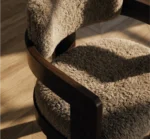 Close-up of luxury dining chair with plush textured upholstery and wood armrest