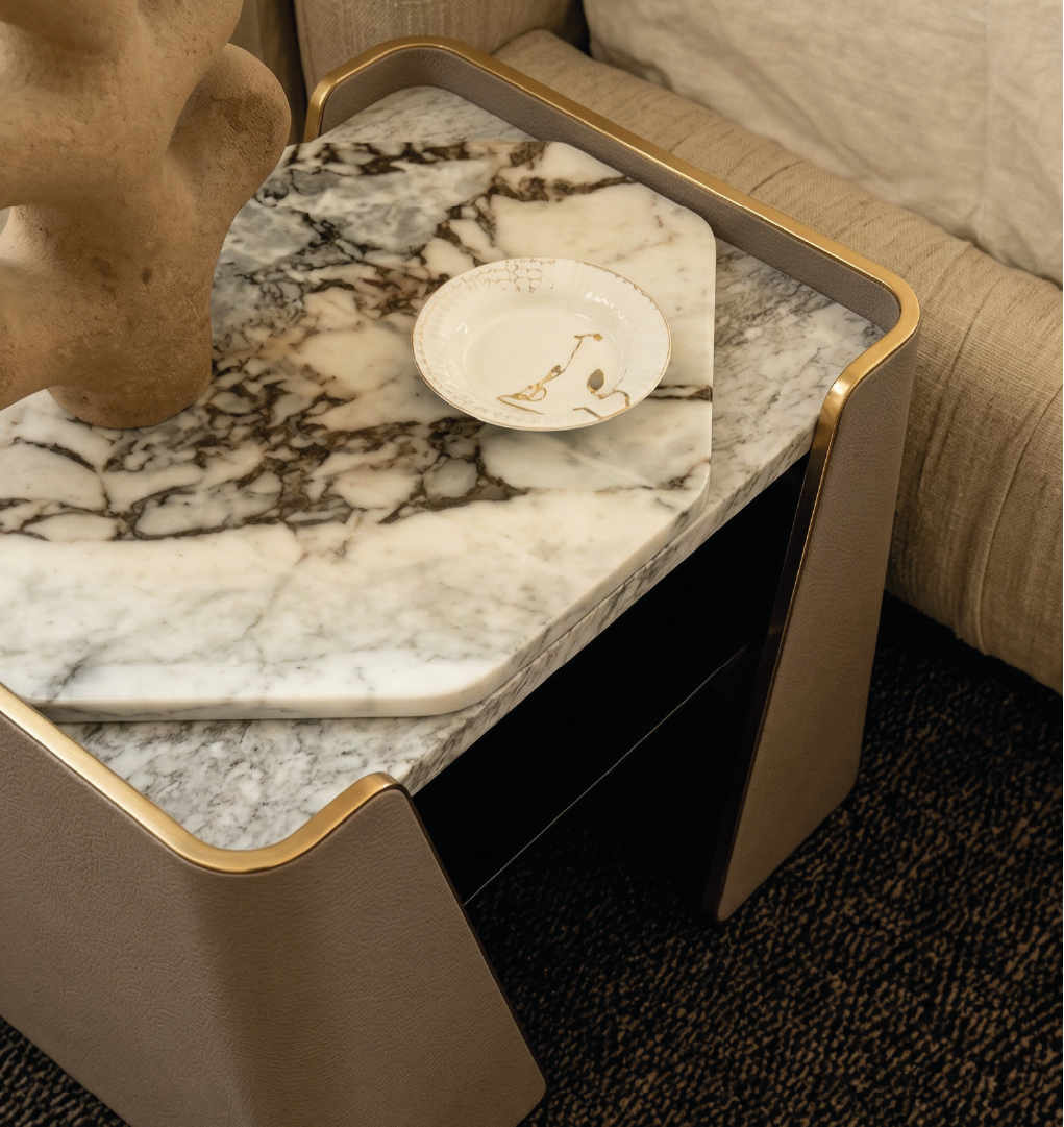 Close-up of Tallis nightstand with marble top, leather frame, and decorative objects in modern interior.