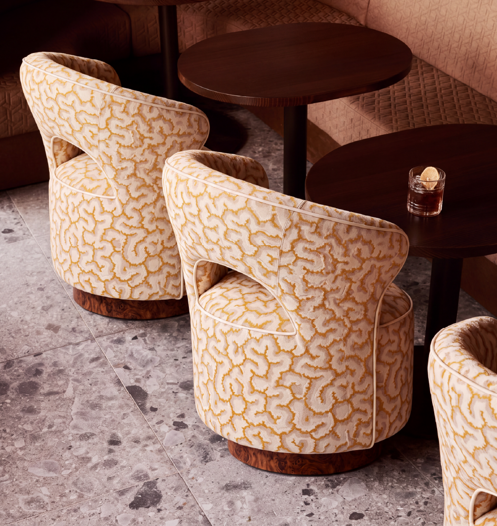 Bizet dining chairs in cream and gold patterned upholstery with walnut root wood bases in a luxury restaurant setting