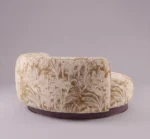 Hedy chaise lounge in cream and gold botanical upholstery with rounded silhouette and dark walnut wood base
